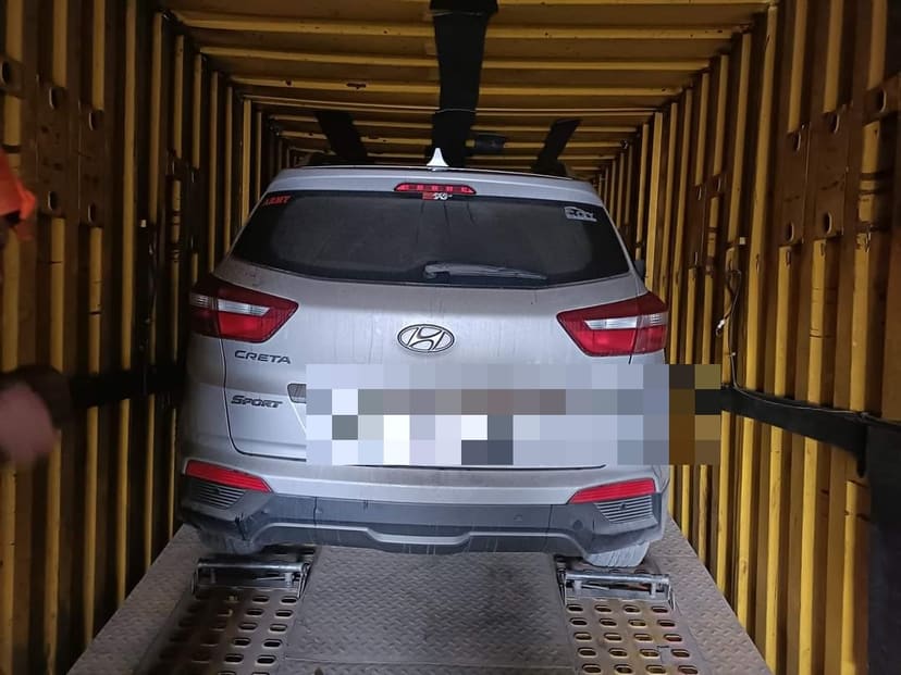 Car secured on the lower deck of an enclosed vehicle carrier