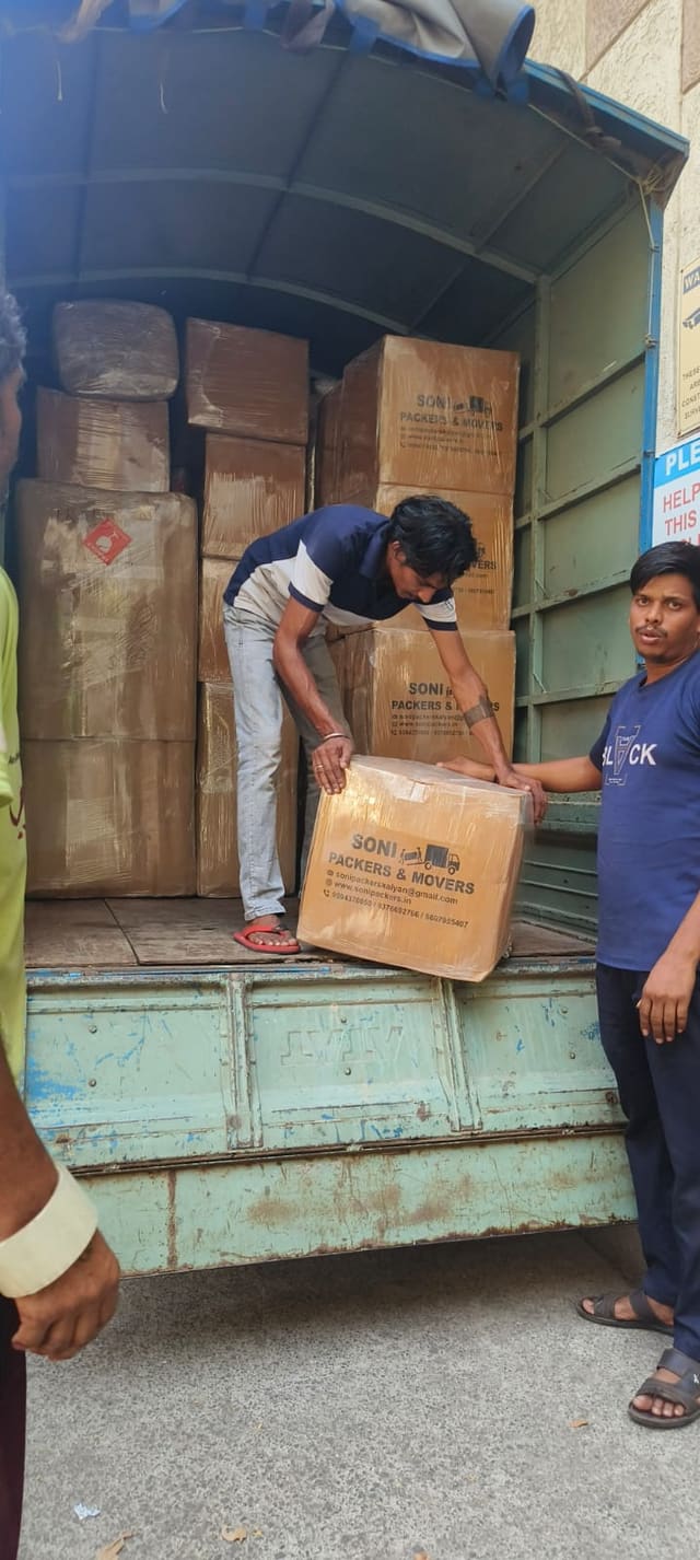 Crew member carrying a packed carton to a waiting goods vehicle