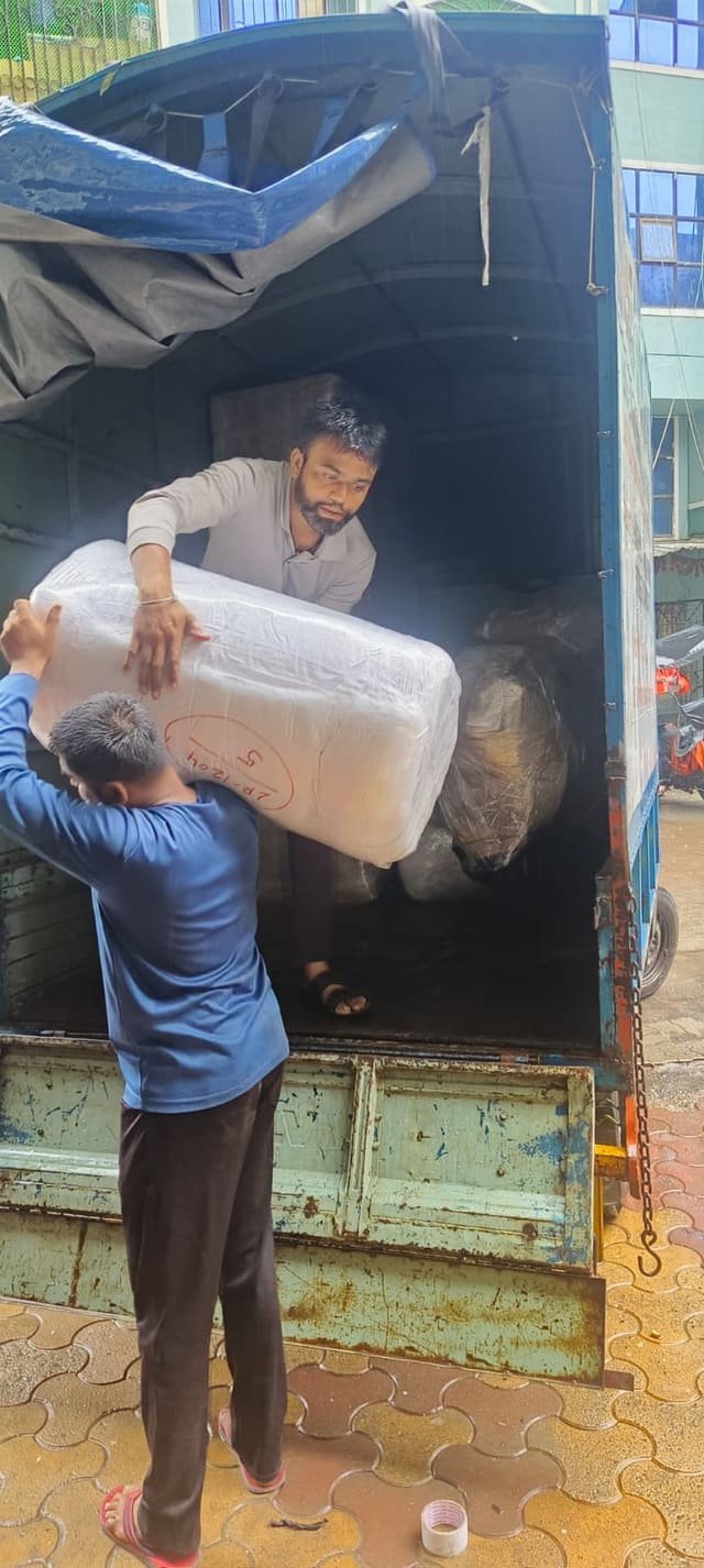 Two crew members lifting a wrapped item into the back of a truck