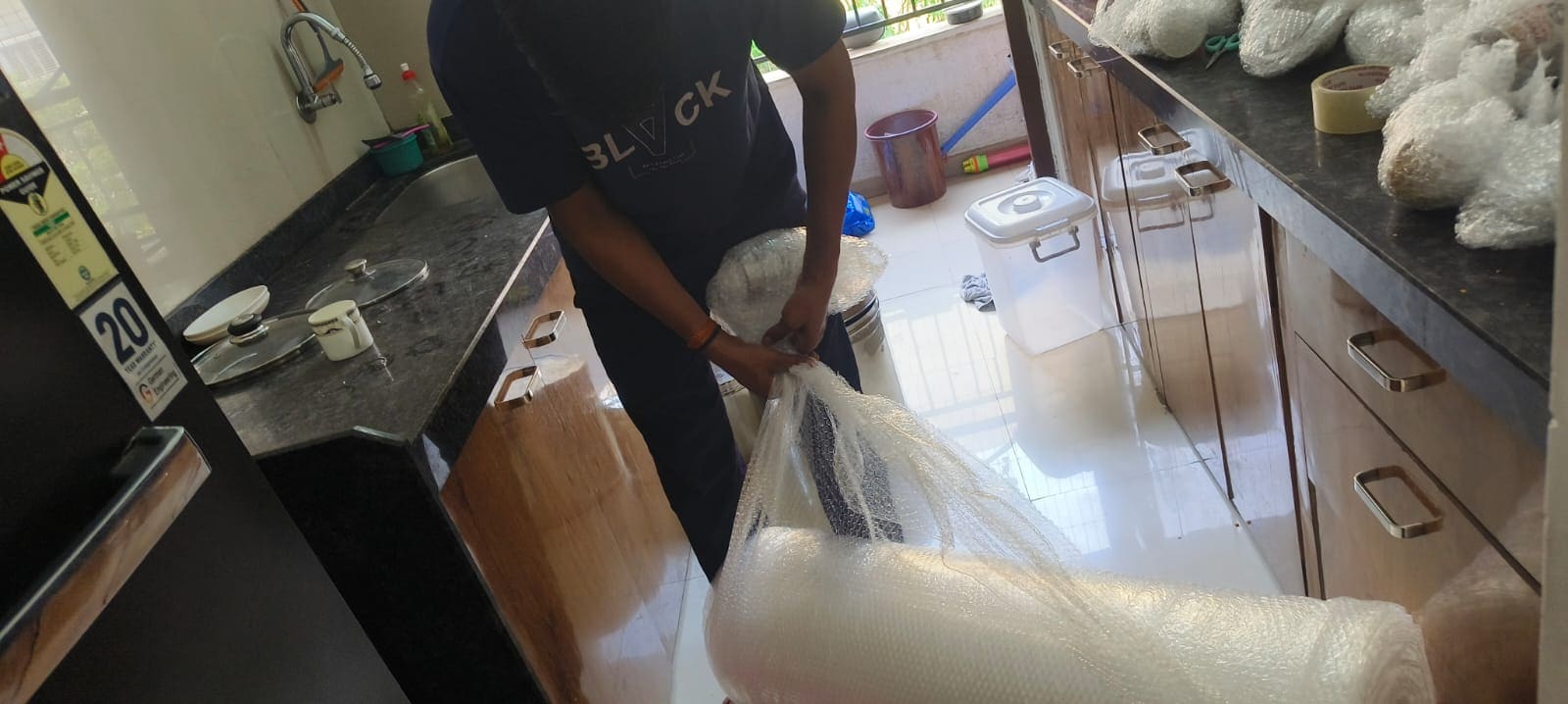 Crew member wrapping kitchen items at a countertop during packing