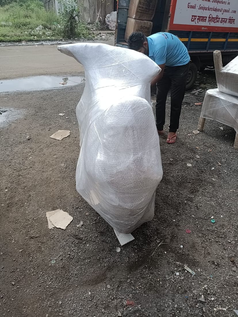 Crew member wrapping a large household item in protective film outdoors