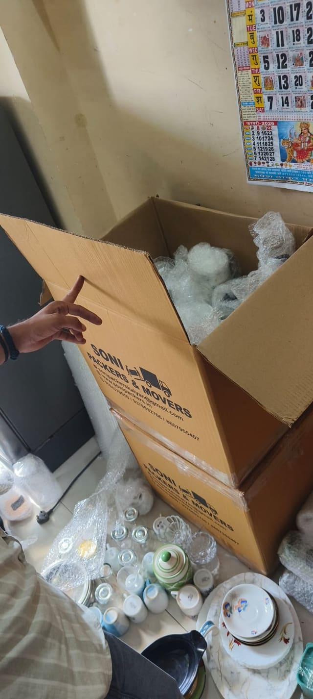 Crockery being packed into a labelled carton with protective wrapping