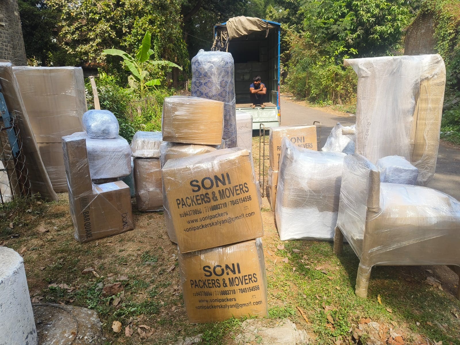 Wrapped furniture and cartons arranged outdoors during a moving job