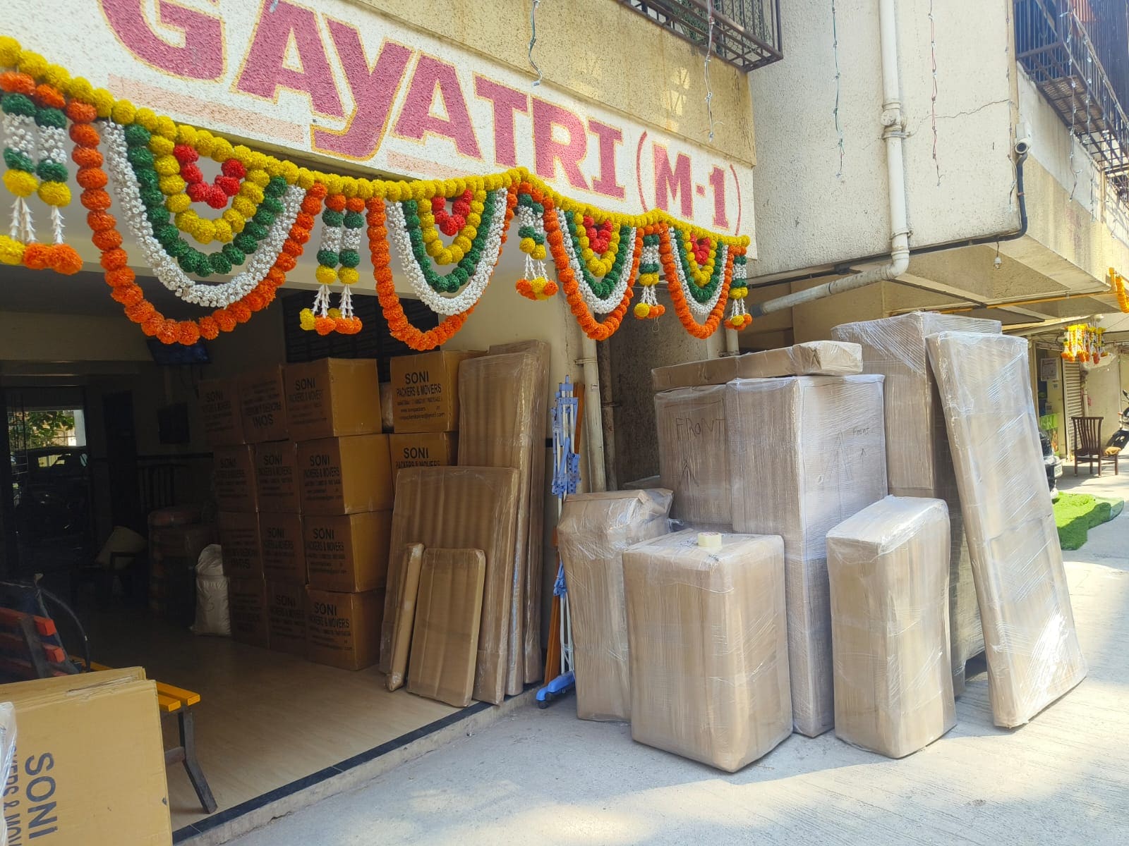 Wrapped household items and cartons arranged outside a building for loading