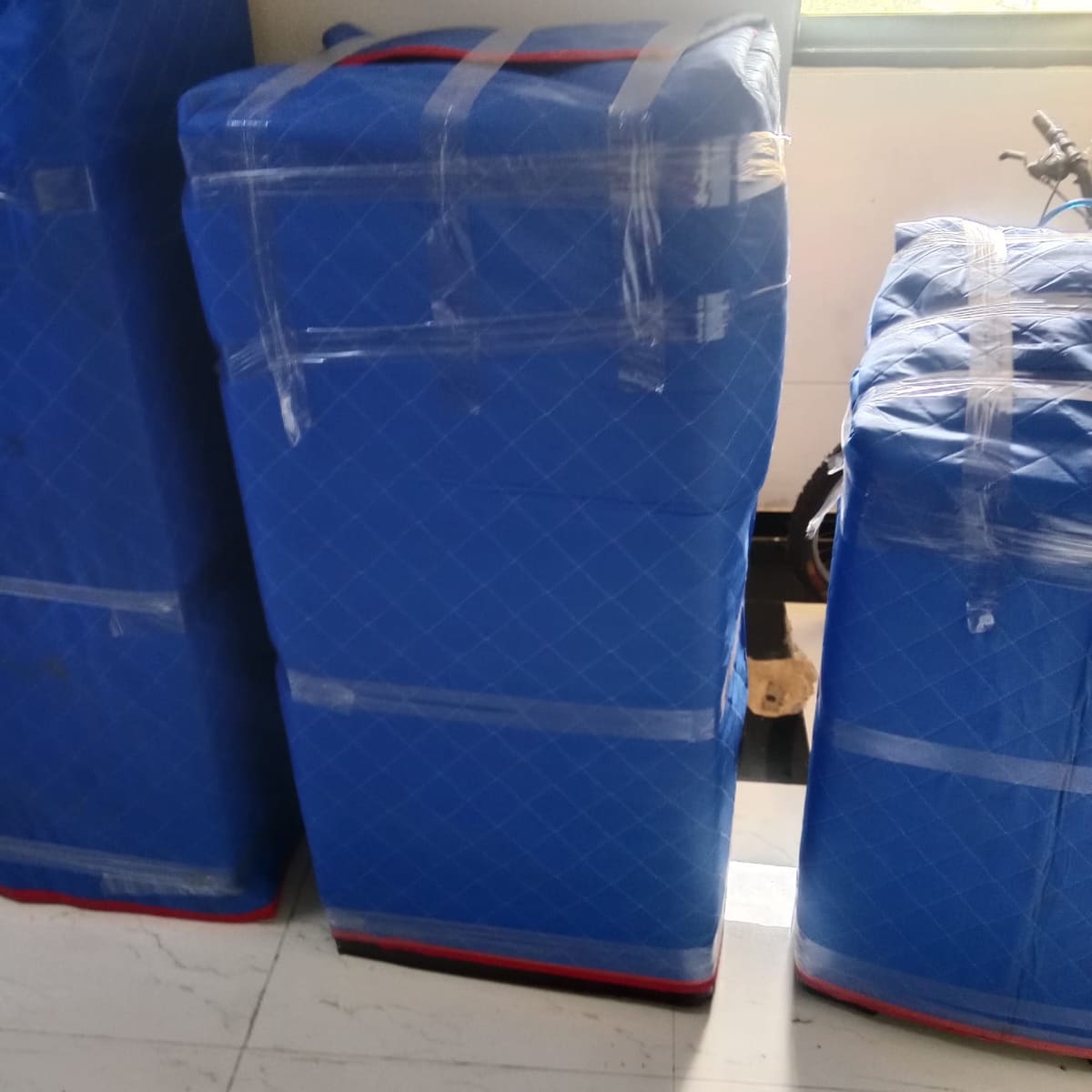Mattresses wrapped in blue protective quilting stacked indoors
