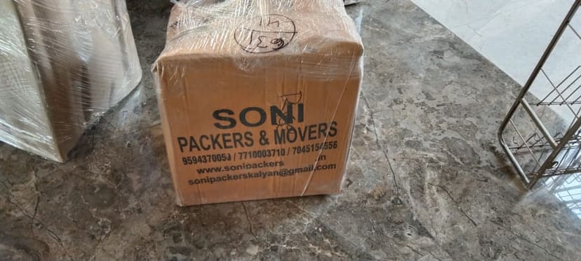 Soni Packers branded cardboard carton wrapped in stretch film on a floor indoors