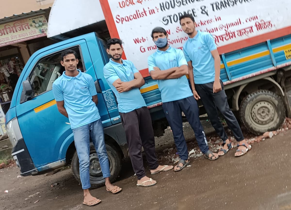 Five Soni Packers crew members in branded uniforms standing beside a company goods vehicle