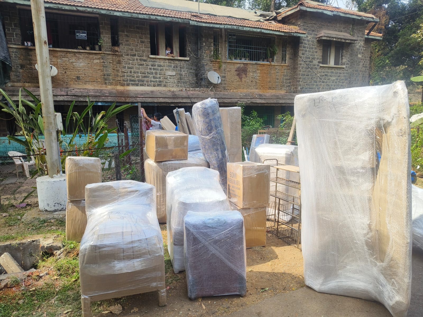 Wrapped furniture and packed goods staged outdoors before loading